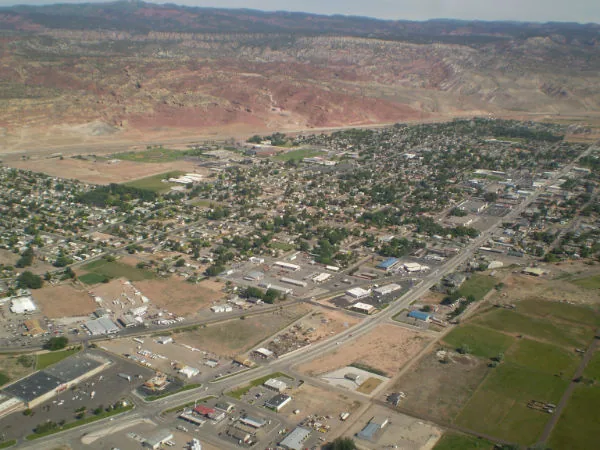 Aerial view of a valley town with green trees and agricultural land surrounded by arid mountains and ridges
