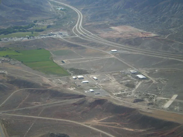 Aerial view of a divided highway winding through agricultural and industrial land with green fields and bare ground